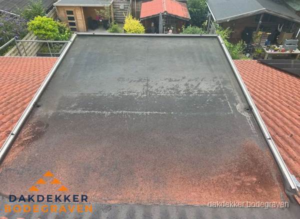 Verouderd plat dak met slijtage tussen schuine daken in Bodegraven Verouderd plat dak met slijtage tussen schuine daken in Bodegraven