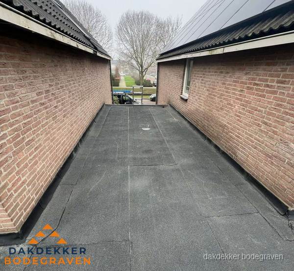 Plat dak met bitumen dakbedekking tussen bakstenen muren in Bodegraven
