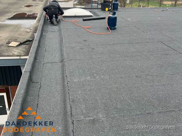 Dakdekker repareert bitumen dakbedekking op groot plat dak in Bodegraven Dakdekker repareert bitumen dakbedekking op groot plat dak in Bodegraven
