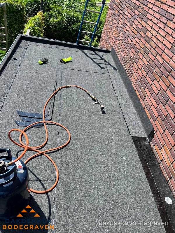 Plat dak met bitumen en brandgereedschap van dakdekkersbedrijf in Bodegraven