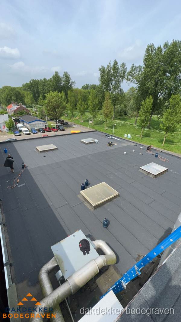 Dakdekker aan het werk op groot plat dak met bitumen in Bodegraven