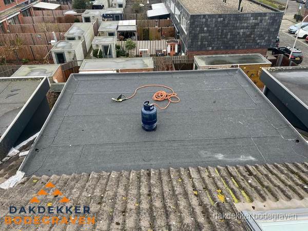 Plat dak met nieuwe bitumen dakbedekking en brandgereedschap in Bodegraven
