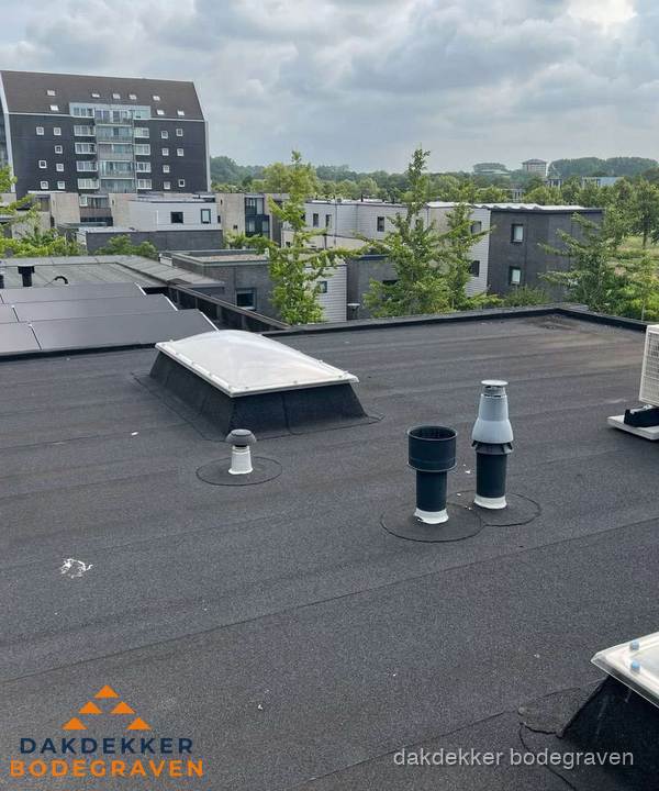 Groot plat dak met lichtkoepel en dakdoorvoeren in Bodegraven
